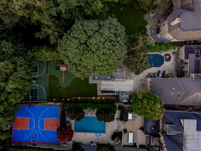 Top-down aerial of a backyard pool and sport court